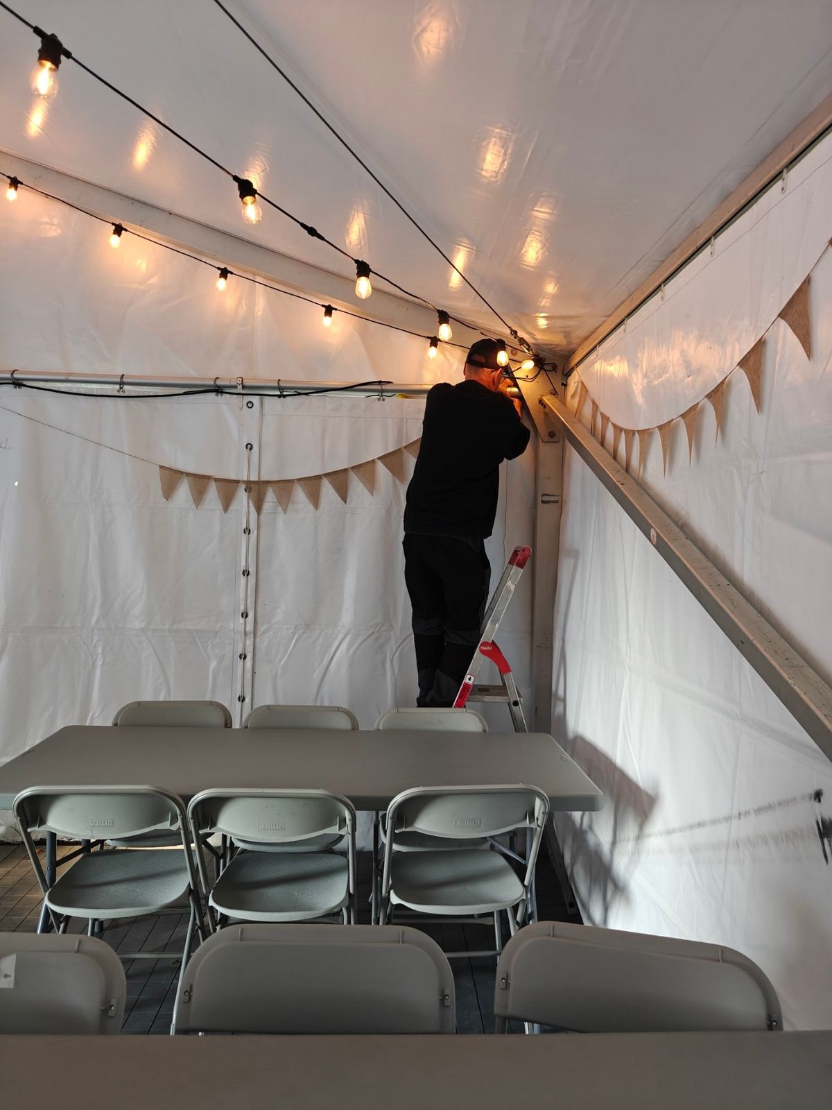Volontär hänger upp ljusslingor i festivaltältet